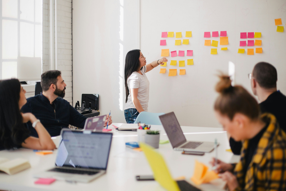 A product manager collaborates with her team to map out features for an AI project. Effective communication and cross-functional teamwork are crucial when managing AI products, as you’ll be aligning data scientists, engineers, designers, and business stakeholders toward a common goal. In high-demand industries like SaaS and healthcare, these brainstorming sessions help ensure that the AI solutions being developed truly address user needs and regulatory requirements.